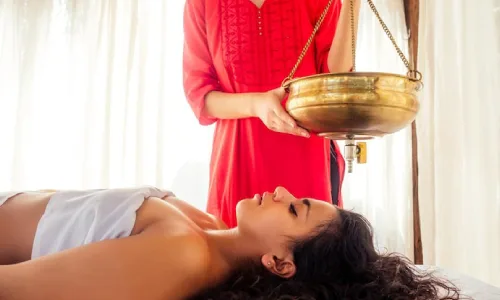 Medicated buttermilk stream poured onto the forehead for stress relief, a cooling effect, anxiety reduction, and mental relaxation, beneficial for calming the mind, soothing headaches, and reducing insomnia.